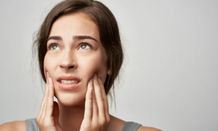 Woman holding her jaw in discomfort from tooth or jaw pain