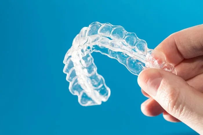 Hand holding a clear aligner tray used to straighten teeth
